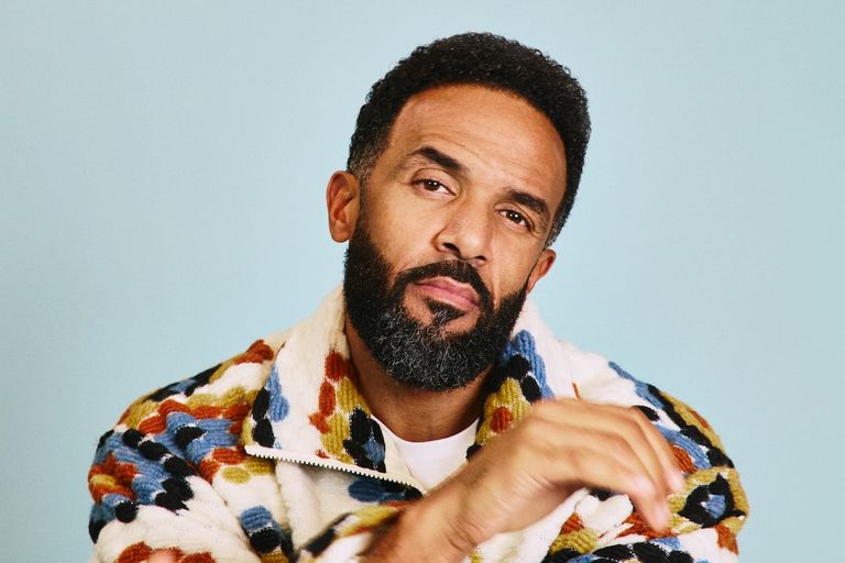 Portrait of singer-songwriter Craig David wearing a patterned fleece jacket against a light blue backdrop.